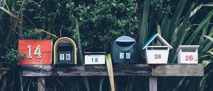  6 different mailboxes with completely different designs all lined up in a row. 