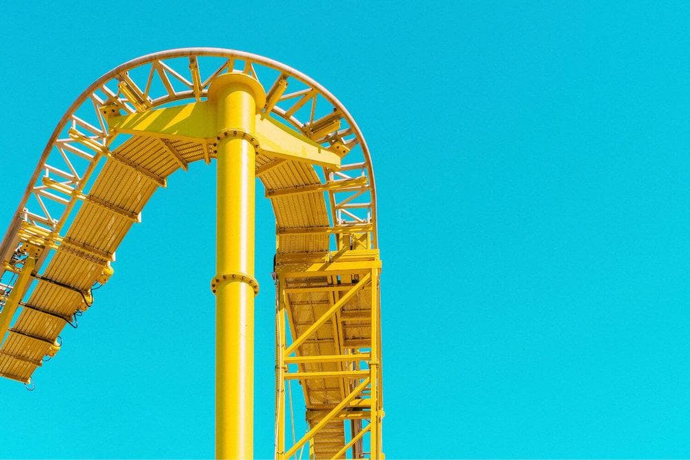  A bright and cheery yellow roller coaster track set against the bright blue sky. 